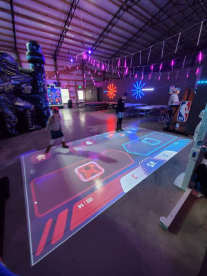 Live-action arcade game room with glowing lights and laser. The