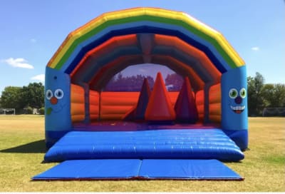 Large Rainbow Castle with Obstacles, a assault course for hire from Happy Days Bouncy Castles