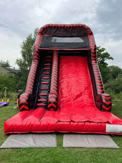 Red black Mega Slide, a inflatable slide for hire from Laxcorp Event Hire