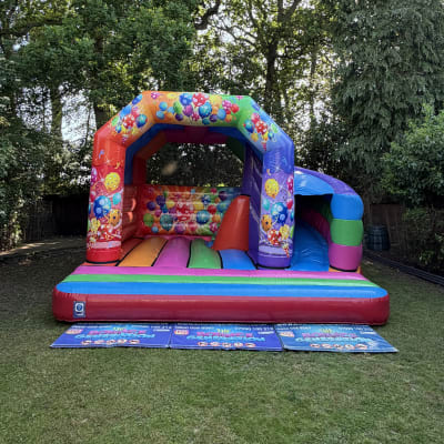 Multi Coloured Party Bouncy Castle with 180 Slide, a bounce and slide combo for hire from The Bounce Generation