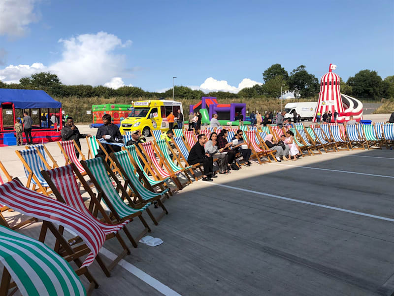 Rows of striped deck chairs at an outdoor fun day with a helter skelter behind