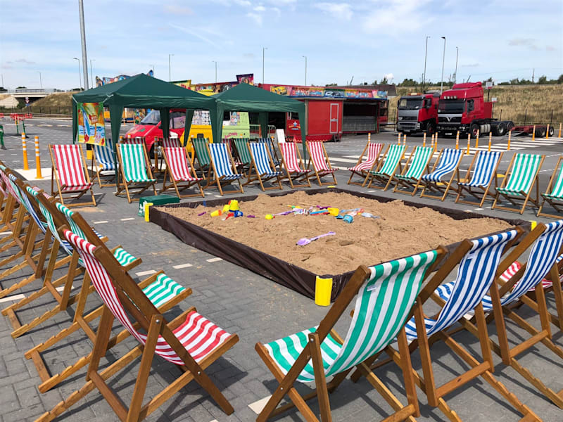 Giant sandpit and striped deck chairs set out in the sun at a family event