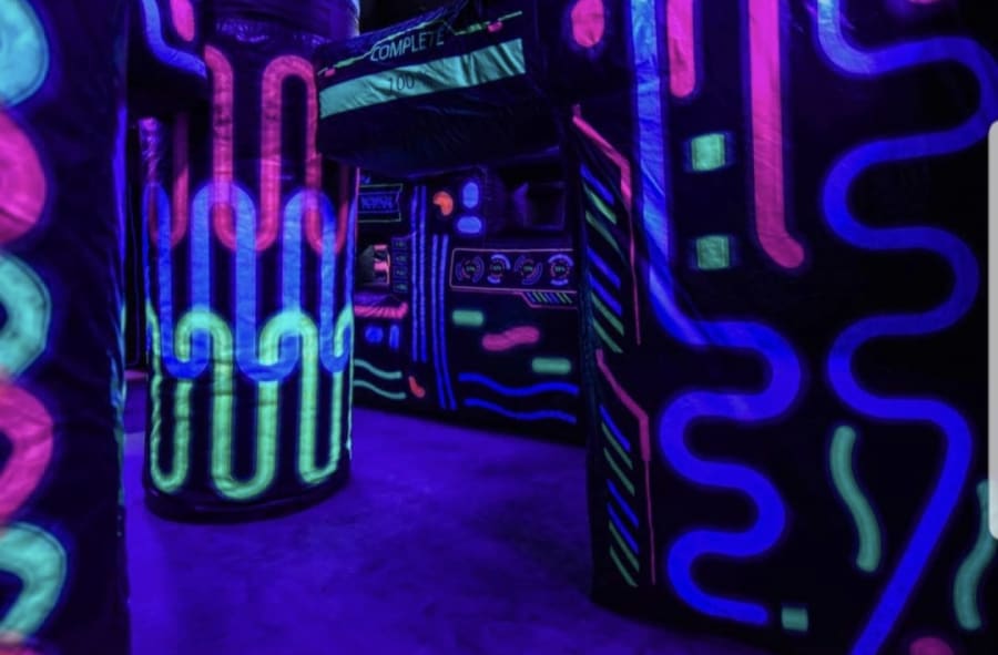 Live-action arcade game room with glowing lights and laser. The